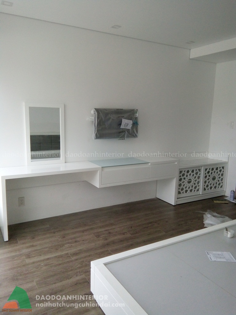 Bộ bàn trang điểm cùng gương được thiết kế gọn gàng trên tường màu trắng với tivi đặt ở giữa